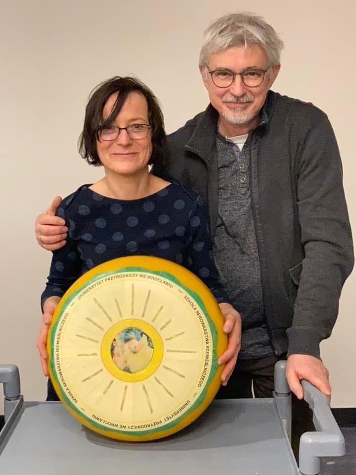 Kobieta i mężczyzna za dużym kołem sera